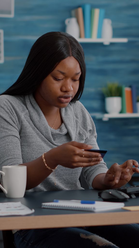 African american student holding cred card in hands doing digital transcation